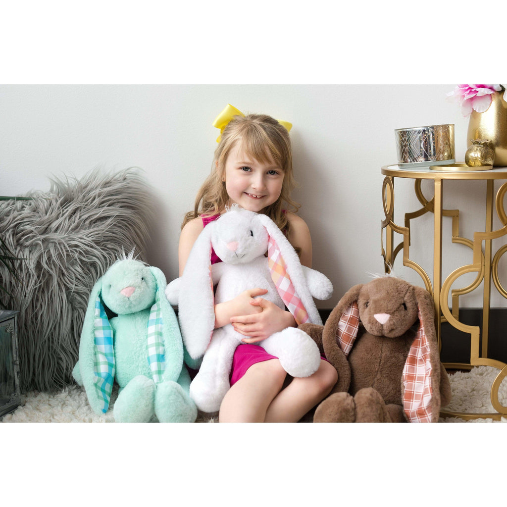 young girl sitting with three large plush bunnies