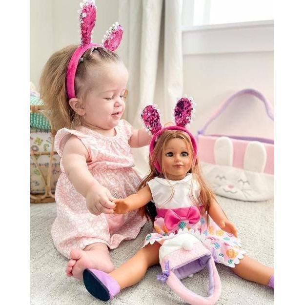 toddler girl wearing bunny ears and holding hands with 18 inch doll